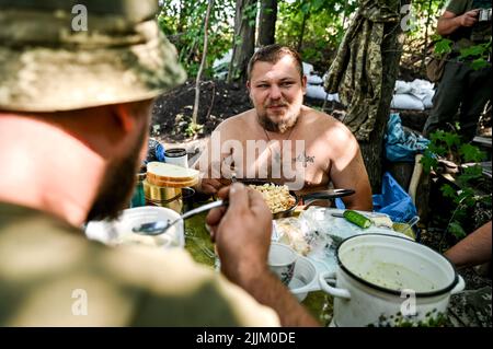 REGION SAPORISCHSCHSCHJA, UKRAINE - 17. JULI 2022 - Militärangehörige der separaten territorialen Verteidigungsbrigade Zaporischschschja speisen an der Front, Saporischschschi Stockfoto