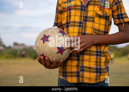 Junge hält einen Fußball auf dem Spielplatz Stockfoto