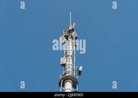 Nahaufnahme eines Telekommunikationsturms mit 5G Mobilfunknetzen auf blauem Himmel Stockfoto