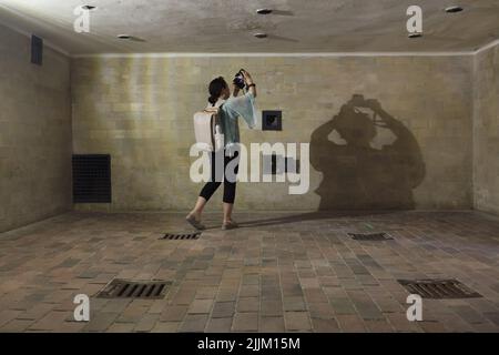 Der Besucher fotografiert in der Gaskammer des großen Krematoriums (Baracke X) im ehemaligen Konzentrationslager Dachau, dem heutigen KZ-Gedenkstätte Dachau in Dachau bei München in Bayern. Das große Krematorium wurde zwischen Mai 1942 und April 1943 errichtet. Das Krematorium diente sowohl als Tötungsanlage als auch zur Entfernung der Toten. Aber die als Brausebad (Duschbad) maskierte Gaskammer wurde nicht für Massenmorde genutzt. Überlebende haben ausgesagt, dass die SS hier jedoch einzelne Gefangene und kleine Gruppen ermordet hat Stockfoto