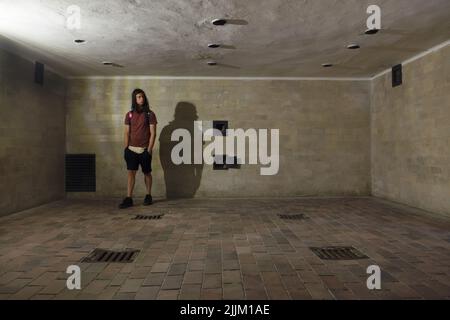 Junger Besucher in der Gaskammer des großen Krematoriums (Baracke X) im ehemaligen Konzentrationslager Dachau, heute KZ-Gedenkstätte Dachau in Dachau bei München. Das große Krematorium wurde zwischen Mai 1942 und April 1943 errichtet. Das Krematorium diente sowohl als Tötungsanlage als auch zur Entfernung der Toten. Aber die als Brausebad (Duschbad) maskierte Gaskammer wurde nicht für Massenmorde genutzt. Überlebende haben ausgesagt, dass die SS hier jedoch einzelne Gefangene und kleine Gruppen mit Gift ermordet hat Stockfoto