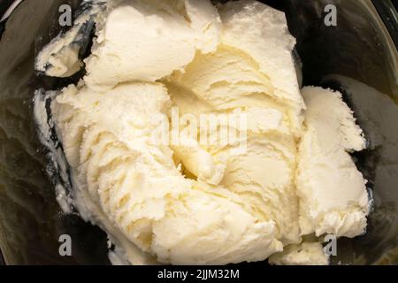 Mehrere Kugeln kaltweißes Eis in einer schwarzen Keramikschale, Makro, Draufsicht. Stockfoto
