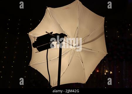 Blitzdiffusor mit einem Regenschirm und einer Halogenlampe. Studio-Diffusor mit weißem Reflektorschirm Stockfoto