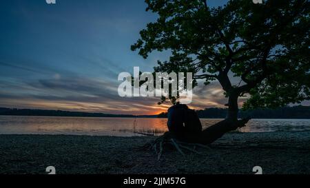 Ein Paar sitzt am Strand und genießt die wunderschöne Aussicht auf den Sonnenuntergang Stockfoto