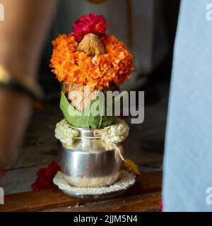 Ein flacher Fokus einer kupferfarbenen Kalasche mit Kokos- und Mangoblatt mit floraler Dekoration in hinduistischer Puja Stockfoto