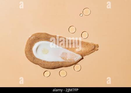 Hautpflegeprodukte Texturen auf beigem Hintergrund. Konzeptuelle, trendige Aufnahme aus Kaffeepeeling, Gesichtscreme und ätherischen Öltropfen Stockfoto