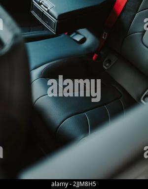 Eine vertikale Aufnahme von Ledersitzen in einem luxuriösen schwarzen Autosalon Stockfoto