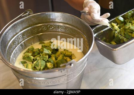 Eine Hand, die gehackte Avocado in einen Backed für die Herstellung von Eis legt Stockfoto