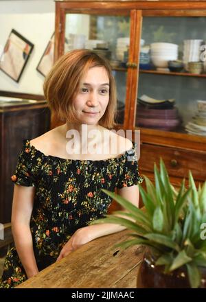 Eine junge Frau, die an einem Holztisch in einem Kaffeehaus sitzt Stockfoto