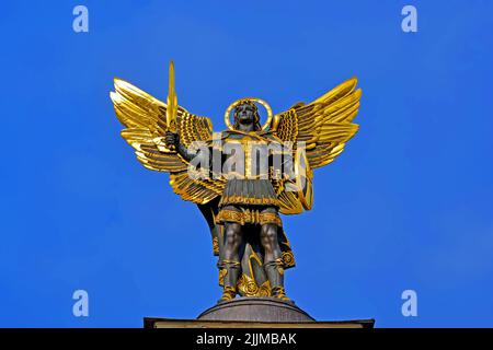 Statue des heiligen Michael auf blauem Himmel in Kiew (Kiew), Ukraine Golden Human mit goldenen Flügeln und Schwert in den Händen. Stockfoto