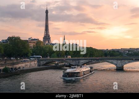 Blick auf den Eifelturm bei Sonnenuntergang mit Brücke und Boot auf der seine in Paris. Stockfoto
