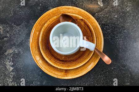 Leeren Sie weiße Kaffee- oder Teetassen auf einer braunen Untertasse auf dunklem Tischhintergrund. Hochwertige Fotos Stockfoto