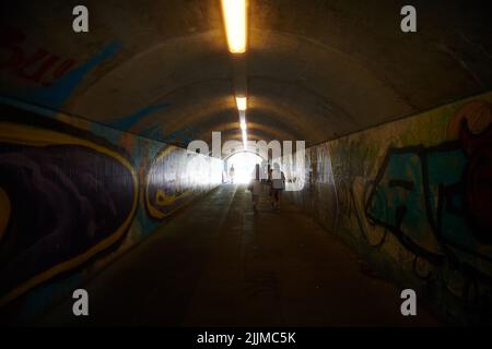 Menschen, die durch einen Tunnel in der Innenstadt von München gehen Stockfoto