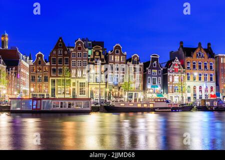 Amsterdam, Niederlande. Farbenfrohe Tanzhäuser am Damrak-Kanal. Stockfoto