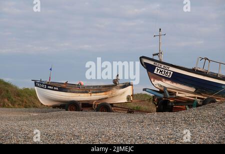 Nahaufnahme von zwei kleinen Fischerbooten an einem Kiesstrand in Weybourne, Norfolk, Großbritannien Stockfoto