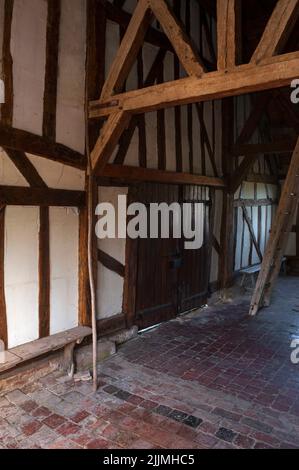 Einfaches, rustikales Interieur der vollständig geschlossenen westlichen Veranda der Fachwerkkirche Église Nôtre-Dame, erbaut Anfang 1500s in Châtillon-sur-Broué in der Marne, Grand Est, Frankreich. Die Veranda ist mit alten roten und schwarzen Fliesen gepflastert und verfügt über einfache Holzbänke und eine alte Holzleiter, die zum schieferhängenden Glockenturm darüber klettert. Nôtre-Dame gehört zu den Kirchen und Kapellen auf einer ausgeschilderten Tour durch die Holzrahmung in der historischen Champagne-Region. Stockfoto