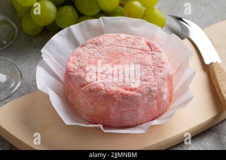 Le Rose, rosafarbener französischer Käse mit Kuhmilch und verfeinert mit Rosé-Champagner aus nächster Nähe auf einem Schneidebrett Stockfoto