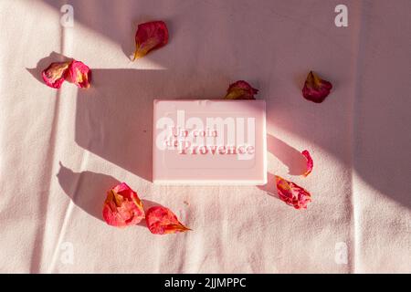 Ein Blick von oben auf die von Rosen duftende quadratische Seife, die von Blütenblättern umgeben ist Stockfoto