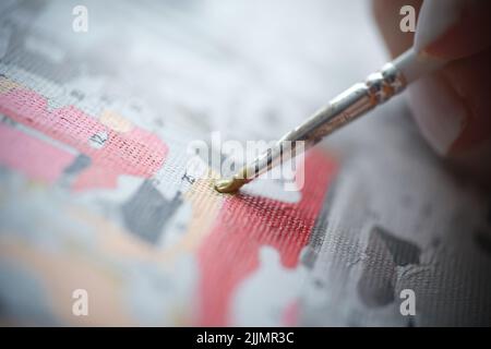 Person hält Pinsel und zeichnet Bild mit Farben nach Zahlen Stockfoto