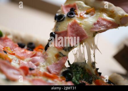 Hand hält Pizzakäse Schinken und Oliven Box Stockfoto