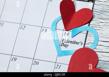 Eine Kalenderseite und Papierherzen am 14. Februar des Valentinstag Stockfoto