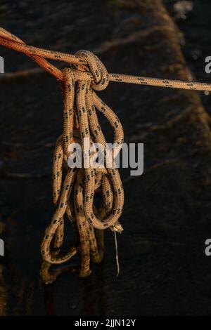 Eine vertikale Aufnahme eines verknoteten Seils auf dunklem Hintergrund Stockfoto