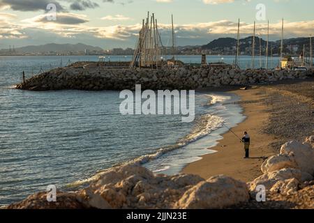 Eine Person, die am Strand von Malaga auf dem Sand läuft Stockfoto