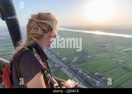 Luxor, Ägypten; 25. Juli 2022 - Eine junge Frau schaut aus einem Heißluftballon, Luxor, Ägypten Stockfoto