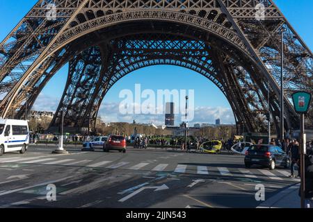 Einige Touristen stehen unter dem Ingenieurskunst-Wunder Eiffelturm in Paris. Stockfoto