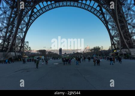 Einige Touristen stehen unter dem Eiffelturm in Paris. Stockfoto