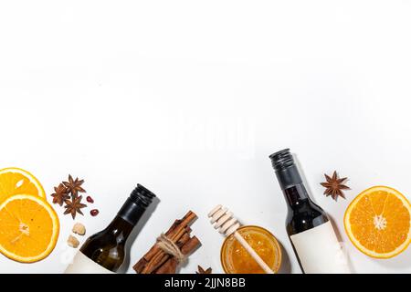 Verschiedene Glühweinzutaten auf weißem Hintergrund, flaches Lay mit Weinflasche, Zimt, Apfel, Orange, Anisstern, Einfaches Herbstessen trinken CO Stockfoto