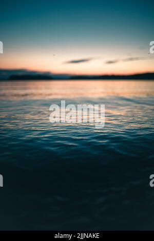 Eine wunderschöne Landschaft aus dunklem tiefem Wasser des Meeres bei Sonnenuntergang Stockfoto