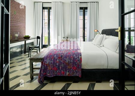 Ein Schlafzimmer mit einem eklektischen Design mit einem bequemen Bett und Zugang zum Balkon. Stockfoto