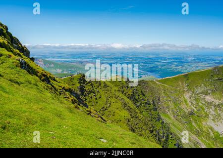 SNOWDON, WALES - 09. JULI 2022: Wanderer bewundern die Aussicht vom Gipfel des Mount Snowdon, dem höchsten Berg in Wales, Stockfoto