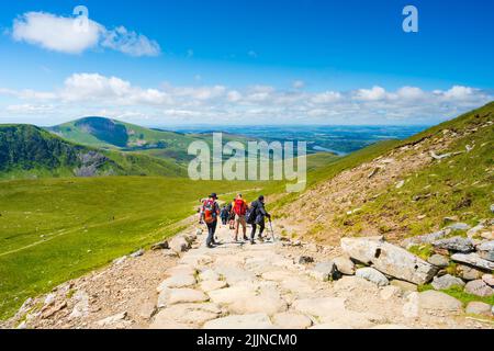 SNOWDON, WALES - 09. JULI 2022: Wanderer gehen vom Mount Snowdon aus nach dem Erreichen des Gipfels in der Morgendämmerung. Snowdon ist der höchste Berg in Wales, Stockfoto