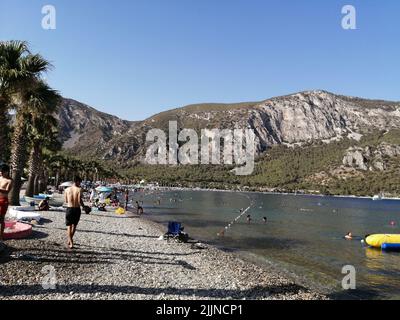 Ein sonniger Tag am Ufer des Sees inmitten von felsigen Bergen Stockfoto