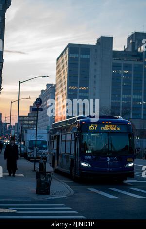 Eine vertikale Aufnahme eines Busses auf einer Straße bei Sonnenuntergang in Brooklyn, USA Stockfoto