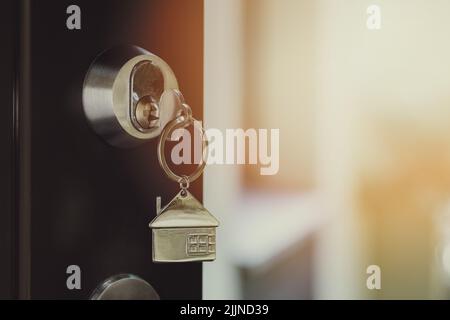 Schlüssel mit Haus Schlüsselanhänger im Schloss der Tür. Kaufen Sie neue Haus-und Eigentumskonzept. Copy space Stockfoto