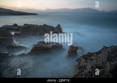 Eine schöne Aufnahme von einigen Felsen im Wasser am Abend. Stockfoto