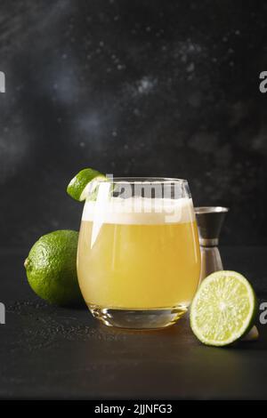 Pisco Sour Cocktail mit Zutaten auf schwarzem Hintergrund. Vertikales Format Stockfoto