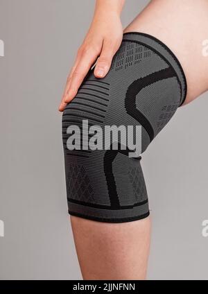 Frau trägt Kniepolster, um Schmerzen zu reduzieren. Verstauchte Bänder, Meniskusriss, Sehnenentzündung, Arthritis. Gesundheitliche Probleme, medizinische Bedingungen Konzept. Hochwertige Fotos Stockfoto
