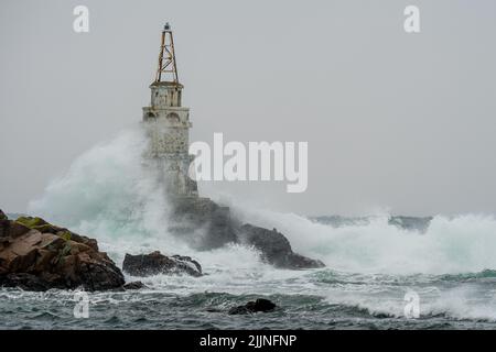Eine große Welle gegen den Leuchtturm im Hafen von Ahtopol, Bulgarien Stockfoto