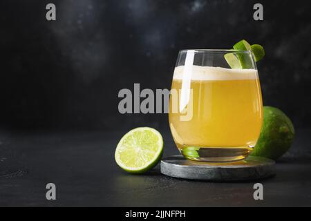 Pisco Sour Cocktail mit Limette auf schwarzem Hintergrund. Horizontale Ausrichtung. Speicherplatz kopieren. Stockfoto
