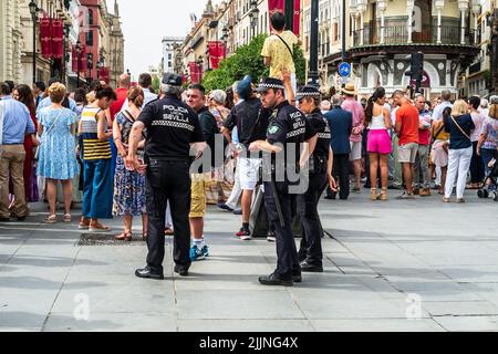 Sevilla, Spanien -- 6. Juni 2022. Polizeibeamte bewachen den Weg, während sich Menschen zur Fronleichnamsprozession versammeln. Stockfoto