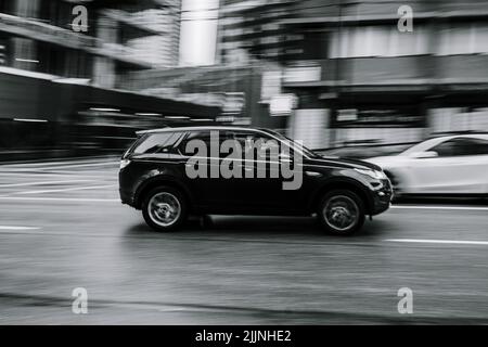 Eine Graustufe eines Range Rover, der eine verregnete Straße in Vancouver entlang fährt Stockfoto