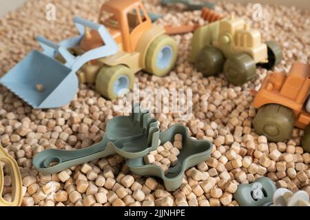 Ein moderner Kinder-Sandkasten mit Spielzeug. Sandkasten-Füllstoff in Form von kleinen Holzwürfeln. Stockfoto