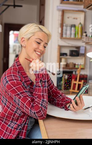 Eine wunderschöne hispanisch-blonde Künstlerin, die in ihrem Studio arbeitet Stockfoto