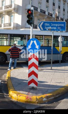 Eine vertikale Aufnahme eines Umgehungsfahrtschilds, einer Ampel und eines Mannes, der vor einem Bus wartet Stockfoto