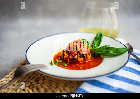 Schüssel mit Fleischbällchen in Tomatensauce mit einem Glas Weißwein Stockfoto