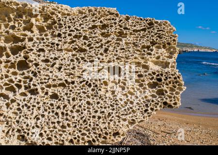 Ein Felsblock aus globigerina Kalkstein nahe der Küste, der an einem sonnigen Tag Anzeichen von Seeverwitterung und Erosion in der maltesischen Landschaft zeigt. Stockfoto